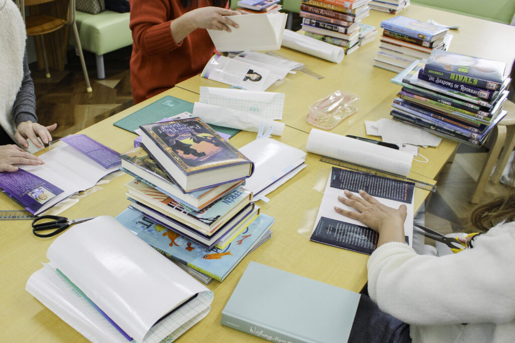 Kumamoto International School parents wrapping books for the school library, supporting IB student learning in Kyushu, Japan.